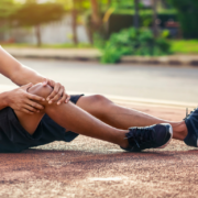 an injured running holding his knee. A pain guide for runners.