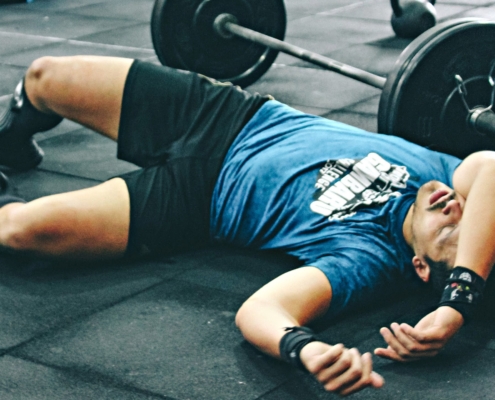 Man laying down in the gym completely exhausted after working out.