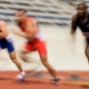 track athletes running fast on a track. The runners are a blur.